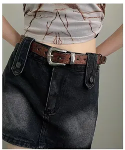 Close-up of retro western style leather belt with ornate vintage buckle worn on denim skirt.