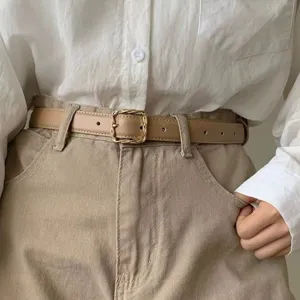 Minimalist women thin leather belt with elegant twisted square buckle for stylish suit pants.