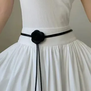 Cinturón fino de cuero negro minimalista con elegante decoración de flor de camelia.