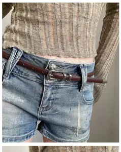 Thin brown leather belt detail shot with vintage metal buckle worn with denim shorts