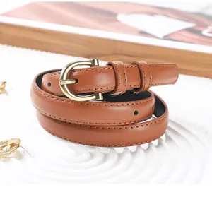 Dettaglio di una cintura sottile in pelle marrone con fibbia in metallo vintage, chic e versatile.