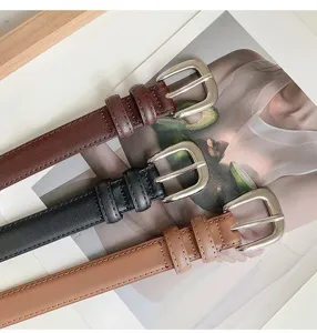 Detailed view of three trendy womens leather belts with classic silver metal buckles.