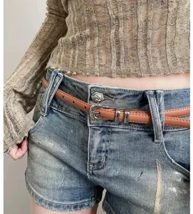 Detailed view of women's thin leather belt styled with vintage denim shorts and top.