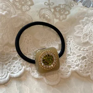 Primo piano dettagliato di un elastico per capelli scintillante con strass su pizzo bianco.