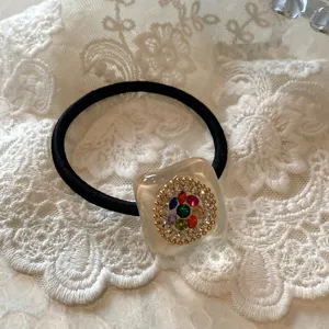 Luminoso elastico per capelli con strass, base quadrata in resina trasparente e fascia nera.