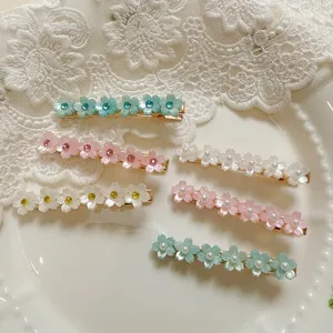 Sweet floral hair clip detail showing sparkling rhinestones and pearls on a dainty side hairpin.
