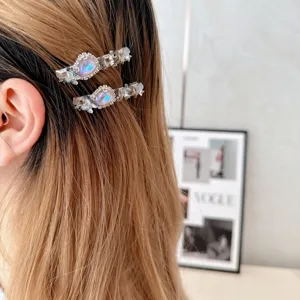 Close-up detail showing sparkling crystal rhinestones and iridescent center stone on side hair clips.
