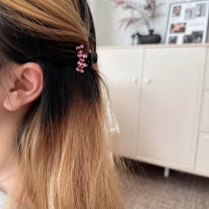 Detailed shot of a mini rhinestone hair claw clip, sparkling pink crystal hair accessory.