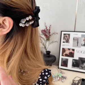Rhinestone bow hair clip detail shot, showing sparkling crystals and black ribbon design.