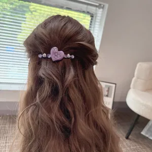 Detailed close-up of the elegant purple heart rhinestone hair clip worn in wavy brown hair.