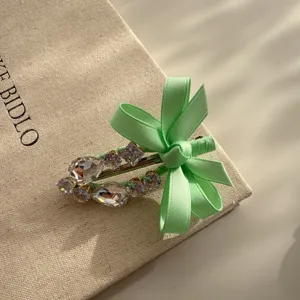Close-up of a sweet light green bow rhinestone duckbill hair clip, elegant and charming detail.