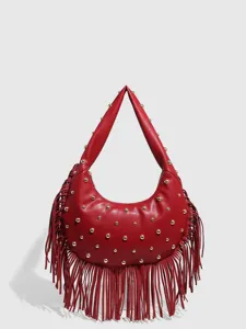 Close-up of red leather crescent hobo handbag featuring gold dome studs and long fringe trim.