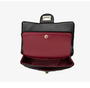 Detail view of the black quilted shoulder bag interior, featuring wine red lining and hardware.