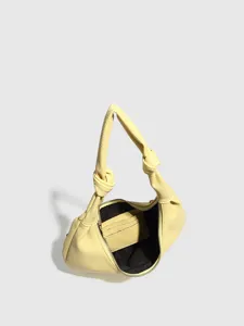 Detailed view of yellow knot handle shoulder bag with zipper and inner card slots.