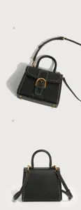 Detail view of black leather top handle bag with horseshoe buckle, contrast stitching design.