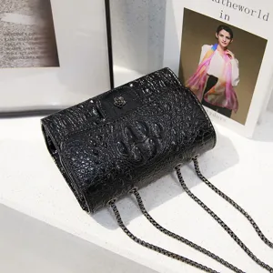Detailed close-up of a stylish black faux crocodile texture crossbody bag with metal chain strap.
