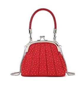 Detailed view of elegant red pearl kiss-lock evening bag with chain strap for party.