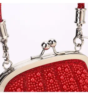 Exquisite red pearl evening bag detail shot, featuring a sleek silver kiss-lock metal frame.