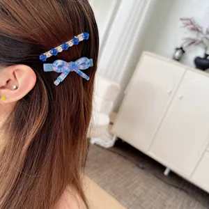 Close-up detail of blue bow and rhinestone hair clips worn on side hair, elegant style.