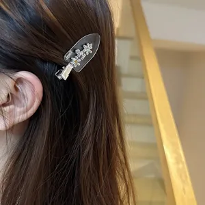 Close-up detail of rhinestone flower hair clip with translucent base worn on brown hair.