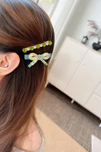 Close-up detail of stylish rhinestone and bow hair clips worn on hair for women daily look.