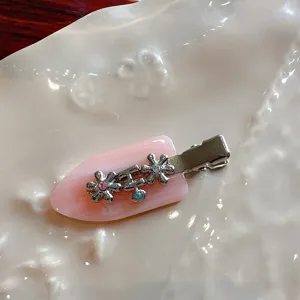 Detail view of pink acetate rhinestone duckbill hair clip featuring cute metal flowers for style.