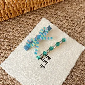 Close-up detail showing a cute colorful striped bow hair clip and green rhinestone barrette.