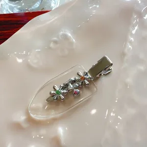 Detailed close-up of a stylish metal flower hair clip with colorful rhinestones on a clear base.