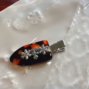 Tortoise shell hair clip detail showing metal flowers and sparkling crystal rhinestones.