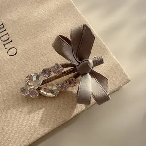 Close-up detail of a sweet grey bow hair clip adorned with sparkling rhinestones for cute style.