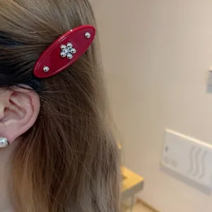 Red acetate hair clip with silver flower detail, sweet side hairpin for women styling.
