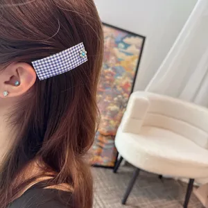 Plaid fabric hair clip featuring a delicate metal flower detail, ideal for daily wear.