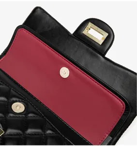 Detailed view of the black quilted shoulder bag featuring burgundy lining and gold tone hardware.