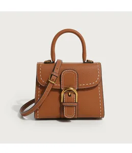 Close-up detail of luxury brown leather handbag with gold D-buckle and contrast stitching.