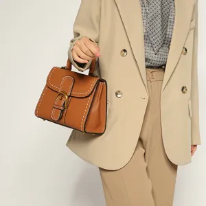 Brown leather top handle handbag with white stitching and elegant horseshoe metal buckle.