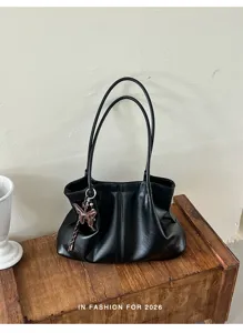 Dettaglio ravvicinato della borsa shopper in pelle PU nera con doppi manici e ciondolo a farfalla.
