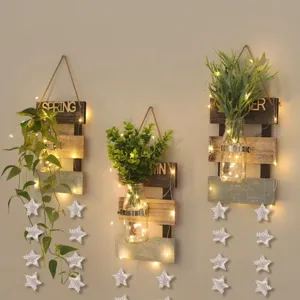 Detailed view of rustic wooden wall hanging decor with jars, green plants and string lights.