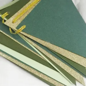 Detail shot of green paper pennant flags with shimmering gold glitter edges for decor.