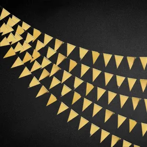 Close-up detail view of shiny gold triangle bunting garlands hanging on dark background.