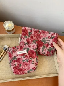 Close up view of vintage dark red rose floral jacquard fabric cosmetic bag with zipper.