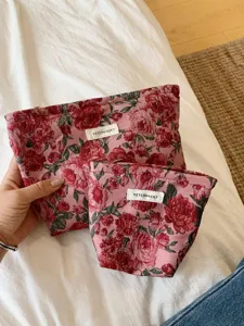 Close-up detail of retro pink red floral jacquard cosmetic bags set with zipper and brand tag.
