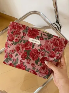 Detail view of vintage red floral jacquard cosmetic pouch, elegant makeup travel storage bag.