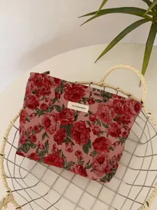 Detail view of a vintage dark red floral jacquard cosmetic bag featuring a secure zipper closure.