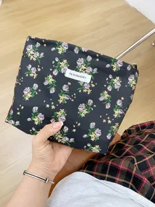 Detail shot of black floral embroidered cosmetic pouch, showing delicate fabric and label.