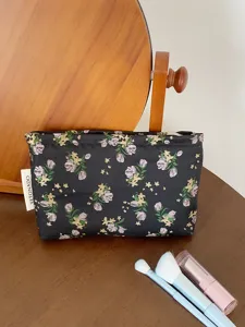 Floral cosmetic bag detail shot, featuring a black fabric with delicate flowers and zip closure.