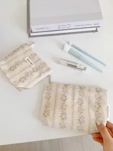 Detailed view of vintage floral makeup pouch, aesthetic flat lay with cosmetic brushes.
