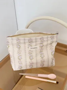 Detail view of vintage floral cosmetic bag with zipper and logo label, portable storage.