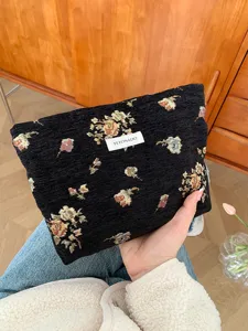 Detailed view of vintage black floral cosmetic bag with gold thread weave and convenient pouch design.