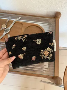 Close-up of vintage black brocade makeup pouch with gold floral weaving and side label detail.