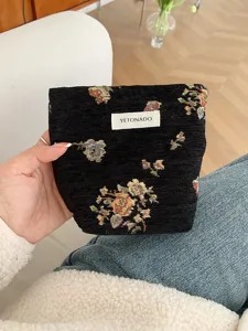 Detailed view of black vintage woven floral cosmetic bag with brand label detail showcase.